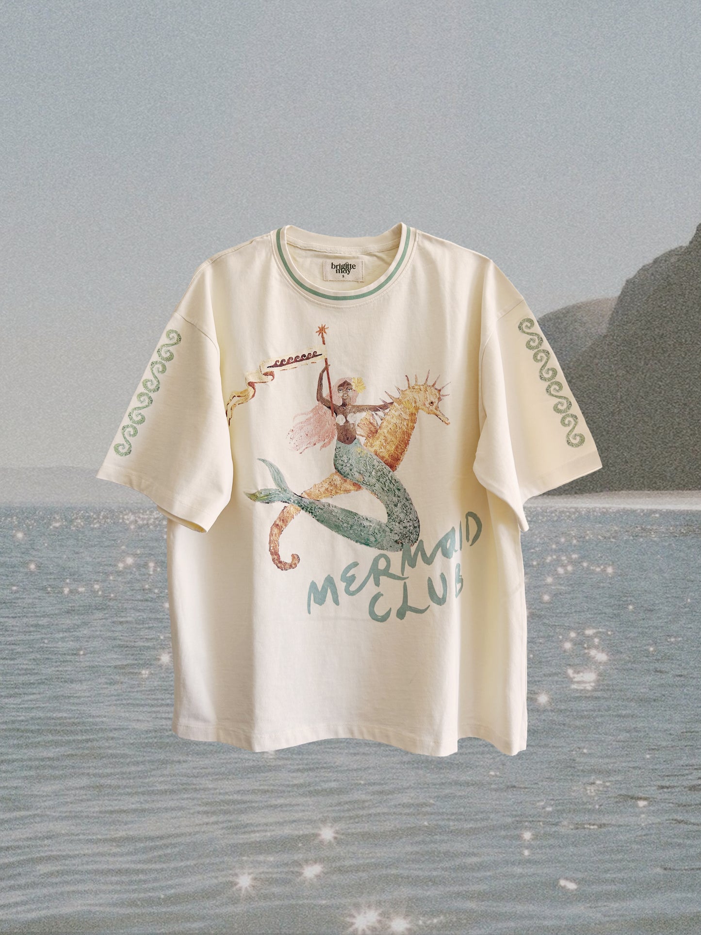White t-shirt with mermaid design and 'Mermaid Club' text on a beach background