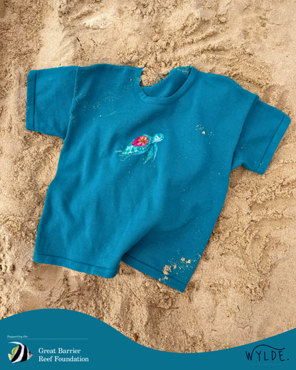 Blue t-shirt with a design on a sandy background, featuring the Great Barrier Reef Foundation logo. Soft organic cotton kids t-shirt supporting reef conservation