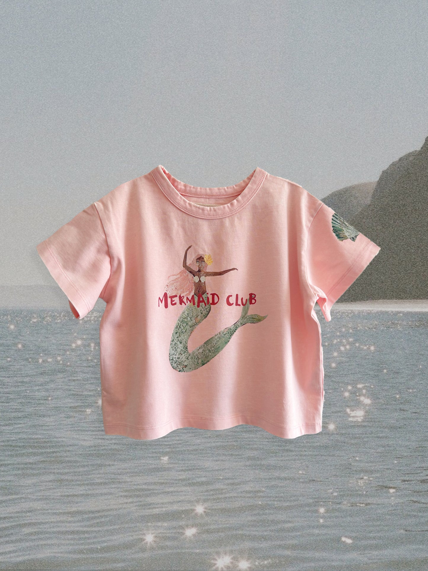 Pink t-shirt with mermaid design and 'Mermaid Club' text on a gray background